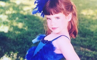 Whitney as a kid dressed up in blue feathers.