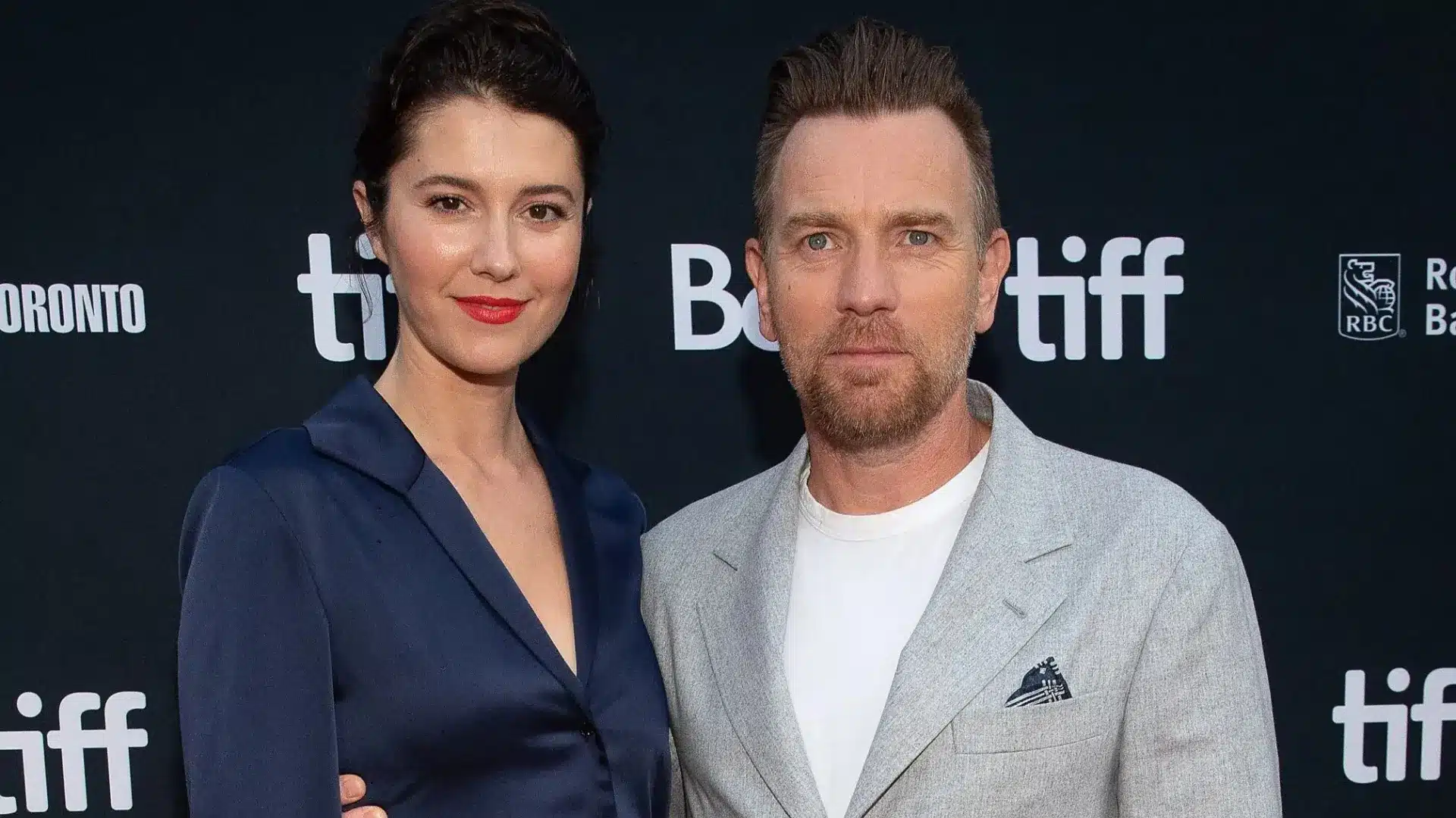Ewan McGregor and Mary Elizabeth Winstead pose together on the red carpet at an event with a black backdrop with logos