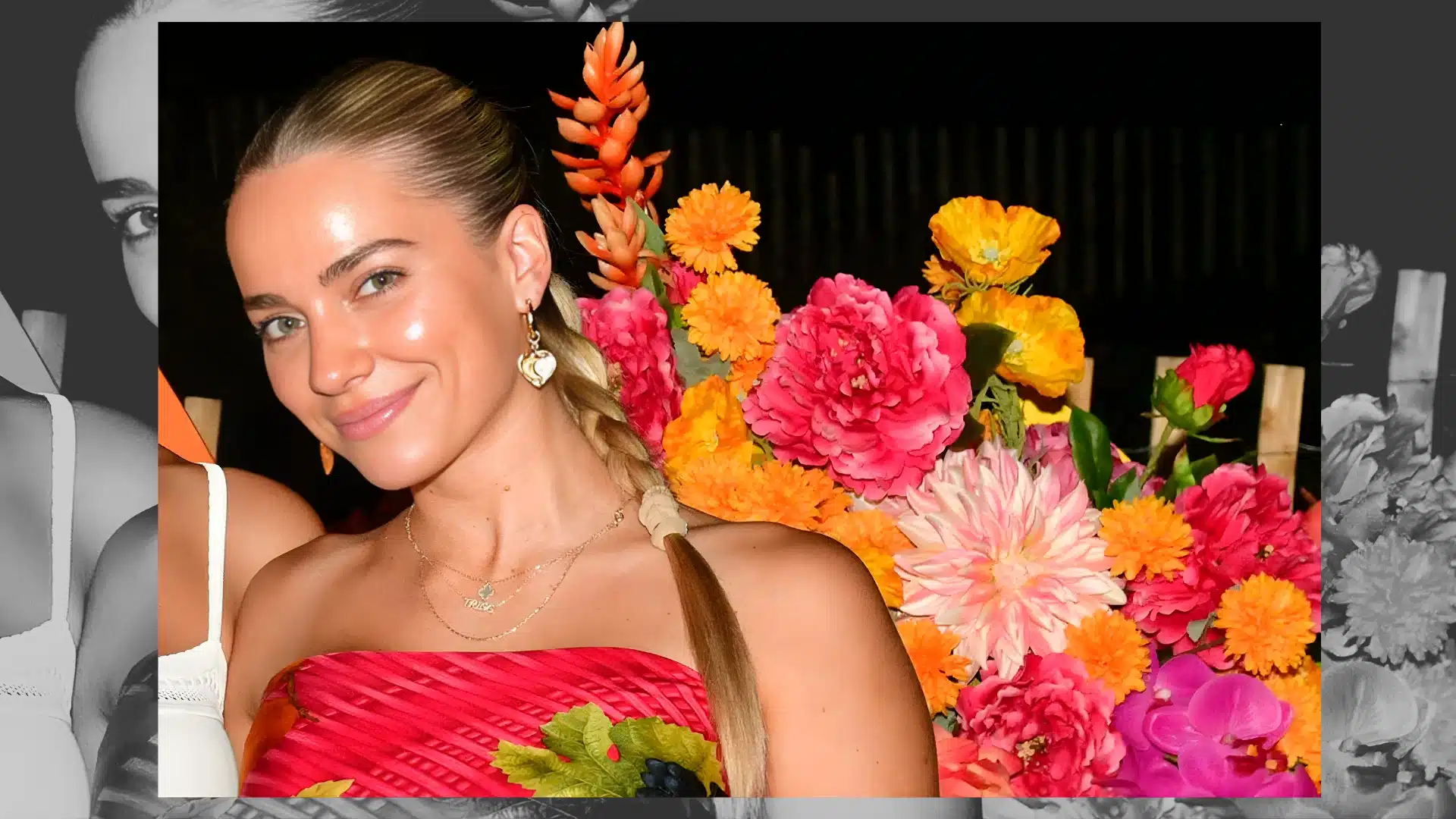 A close up of Emilie Kiser with her blonde hair in a braid smiling in front of a colorful wall of bright orange flowers