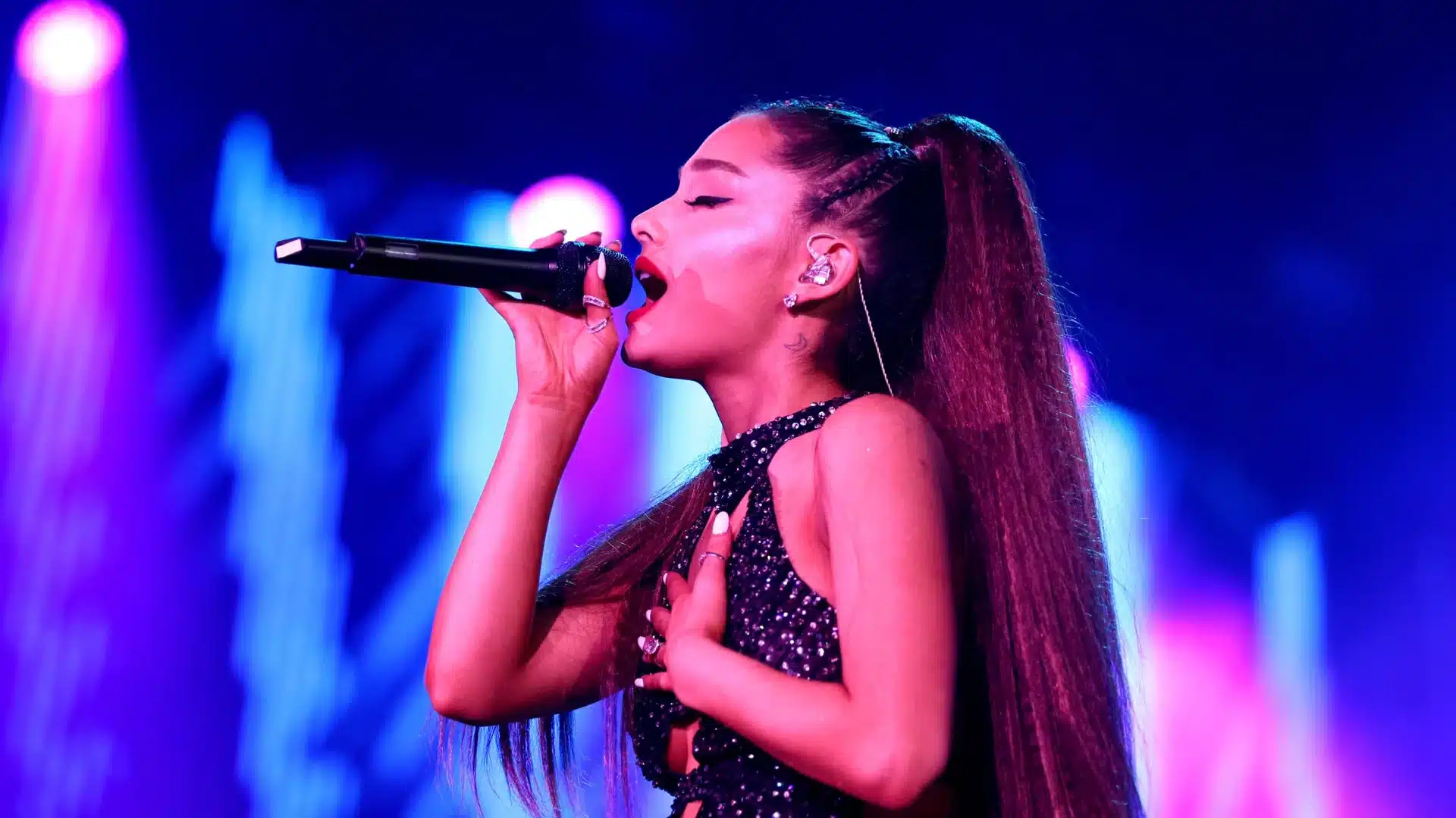 Ariana Grande is singing passionately at her concert after Mac Miller's death, wearing a sparkly black top