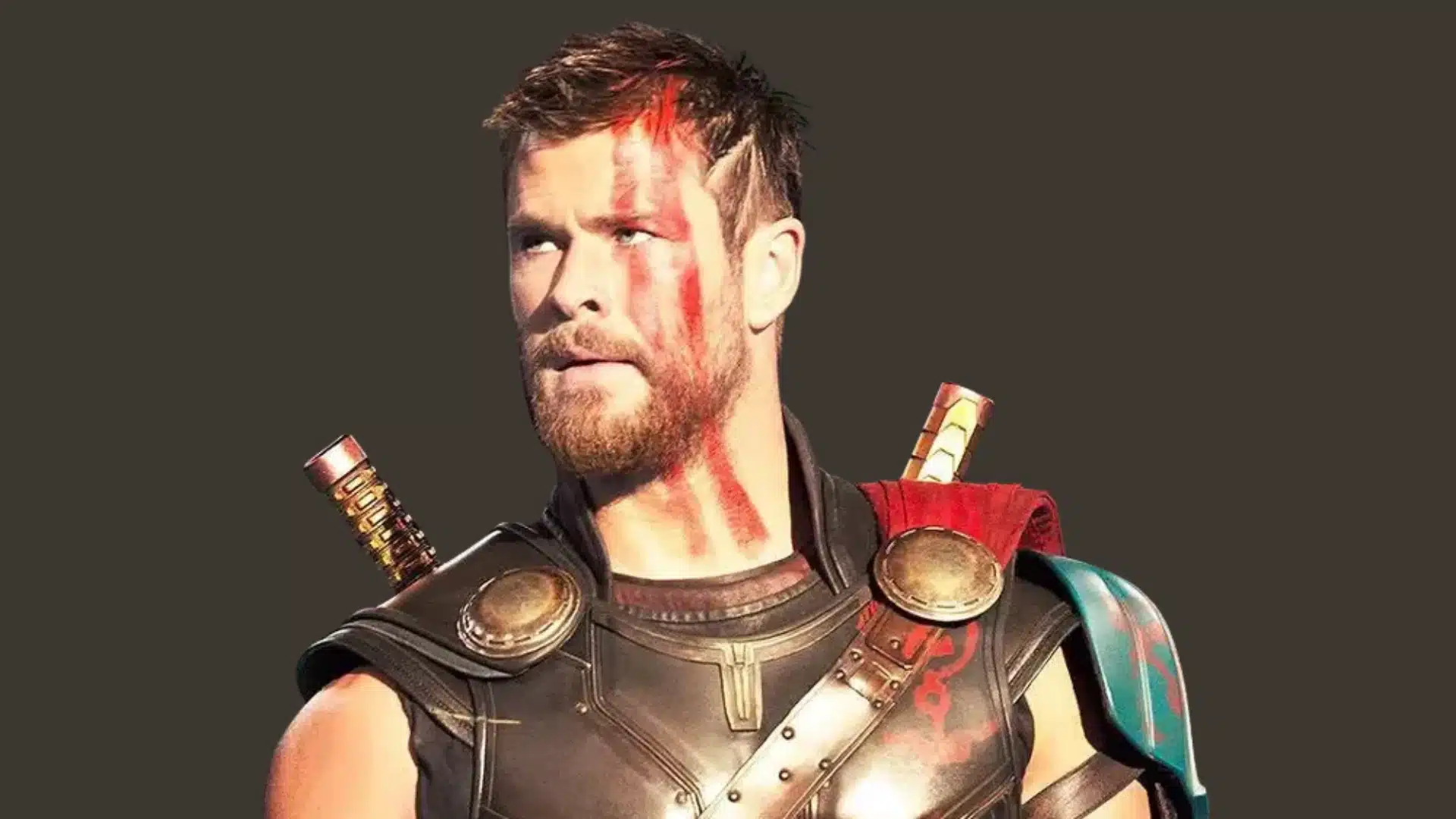 Chris Hemsworth as Thor in his gladiator-style armor with red face and neck paint, set against a dark background