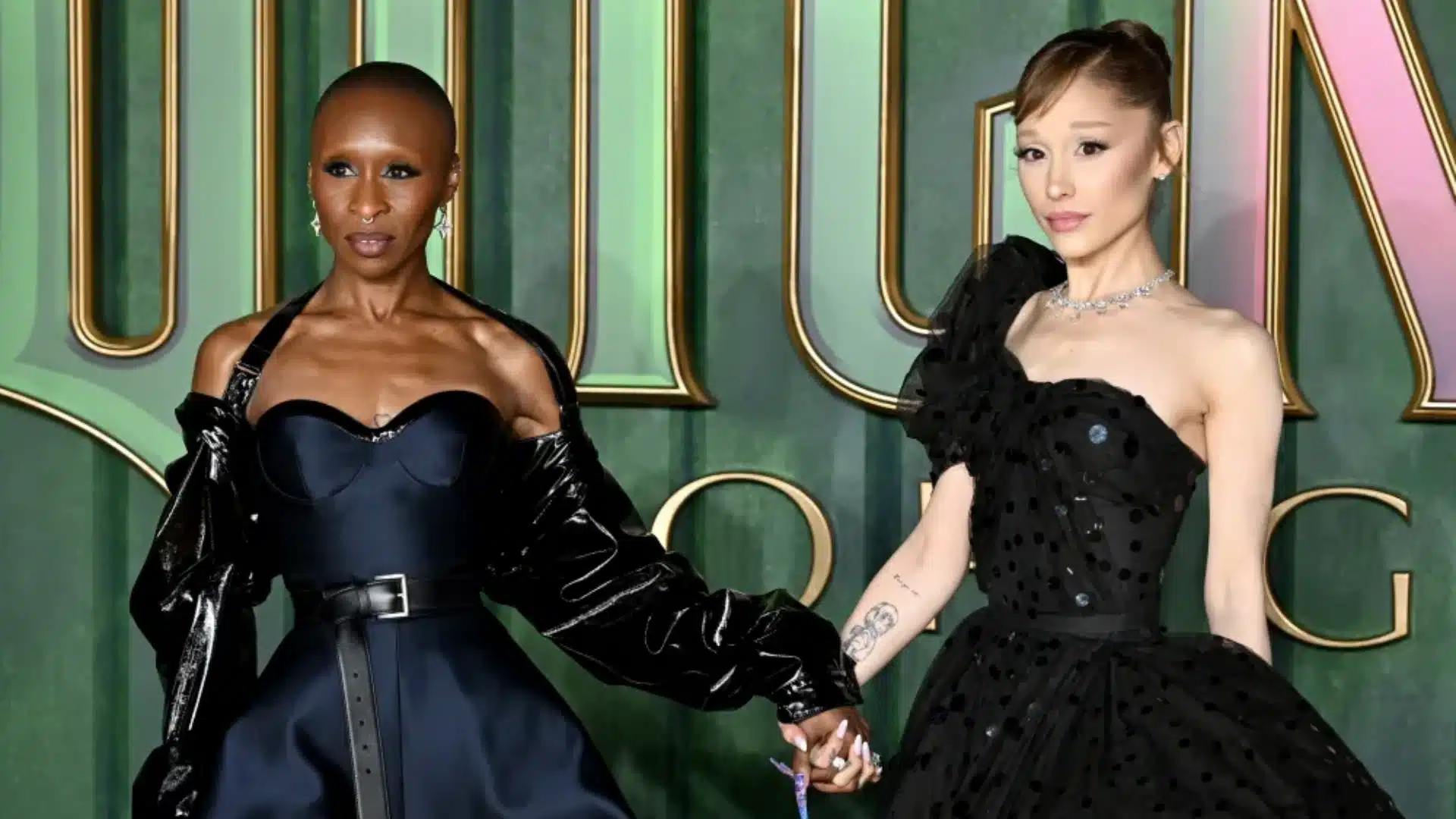 Cynthia Erivo and Ariana Grande are posing together in black formal wear while holding hands at Wicked 2 event