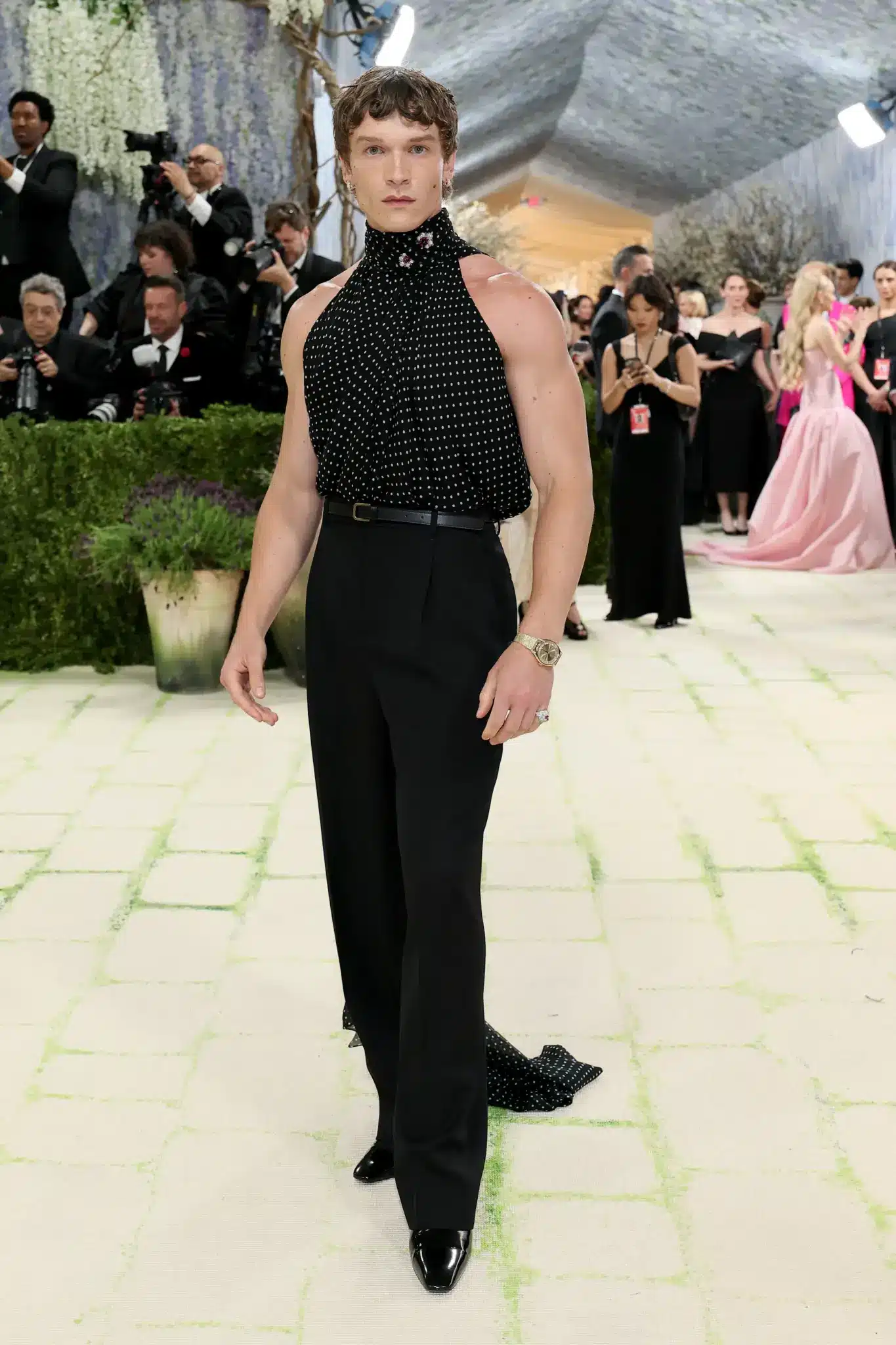 Connor poses in a Saint Laurent polka dot halter top with a long black train billowing behind him