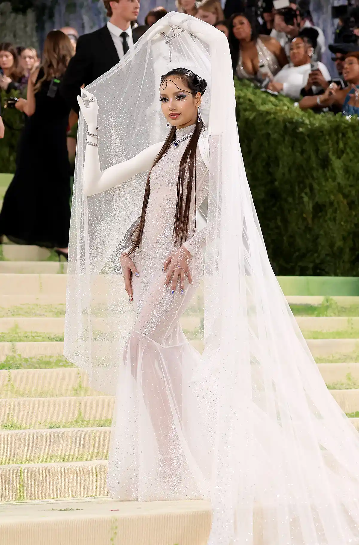 Lisa stands in a sheer Robert Wun gown with 3D printed arms holding a white drape over her head