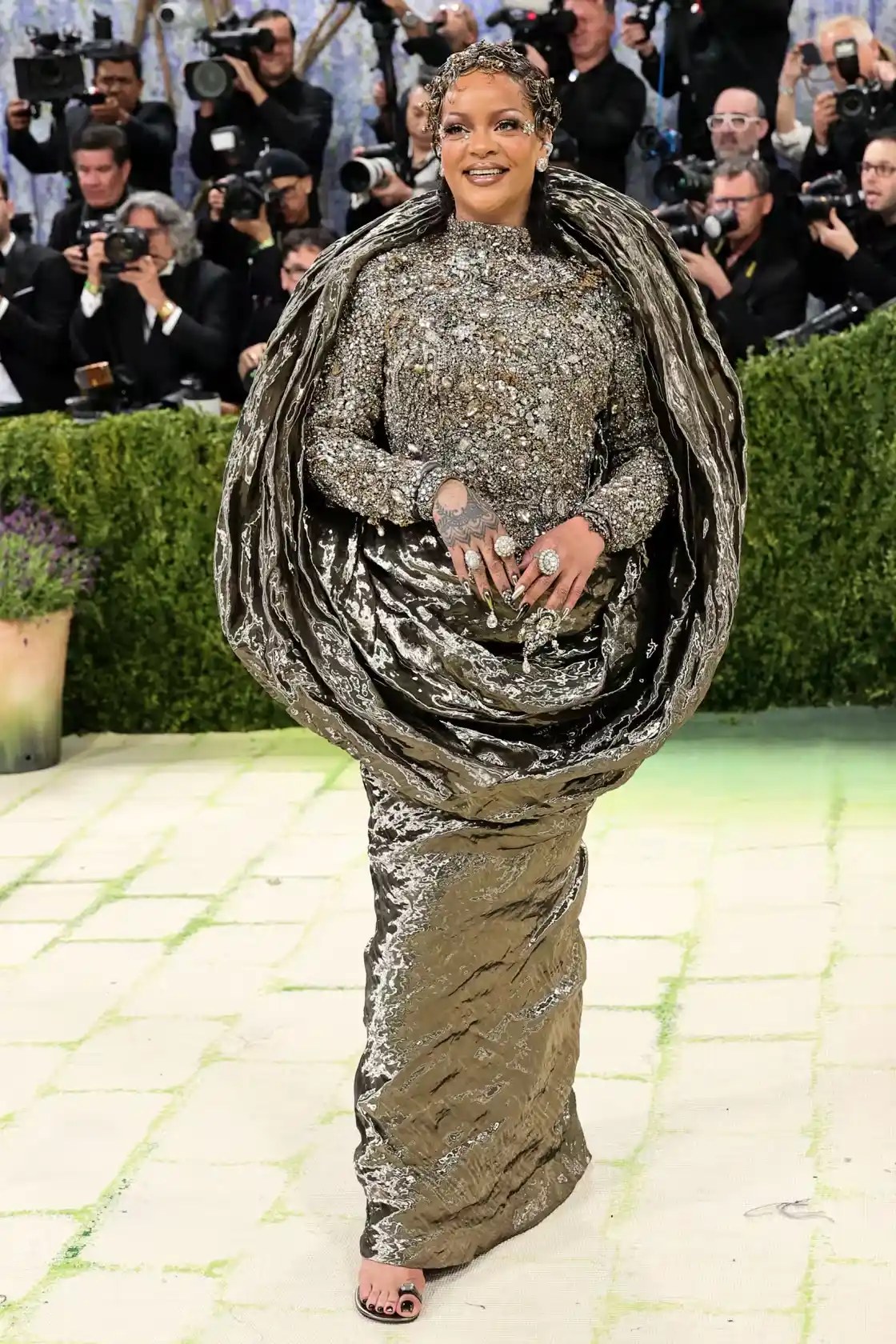 Rihanna stands in a bejeweled Margiela bodice with crinkled fabric wraps and gold curled hair framing her face