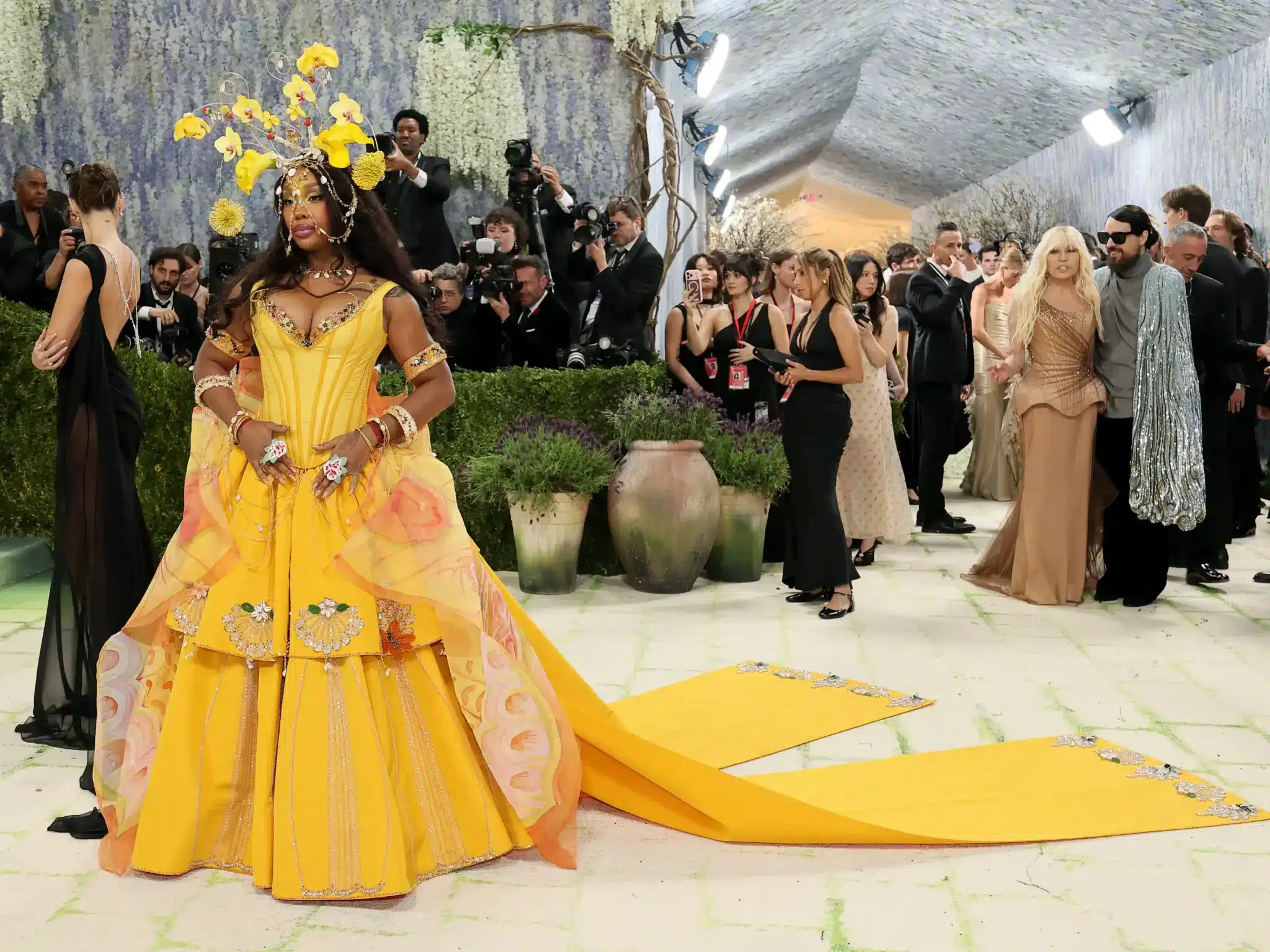 SZA wears a yellow Emily Bode floral dress with a lunar moth train and a sculptural headpiece on the carpet (1)