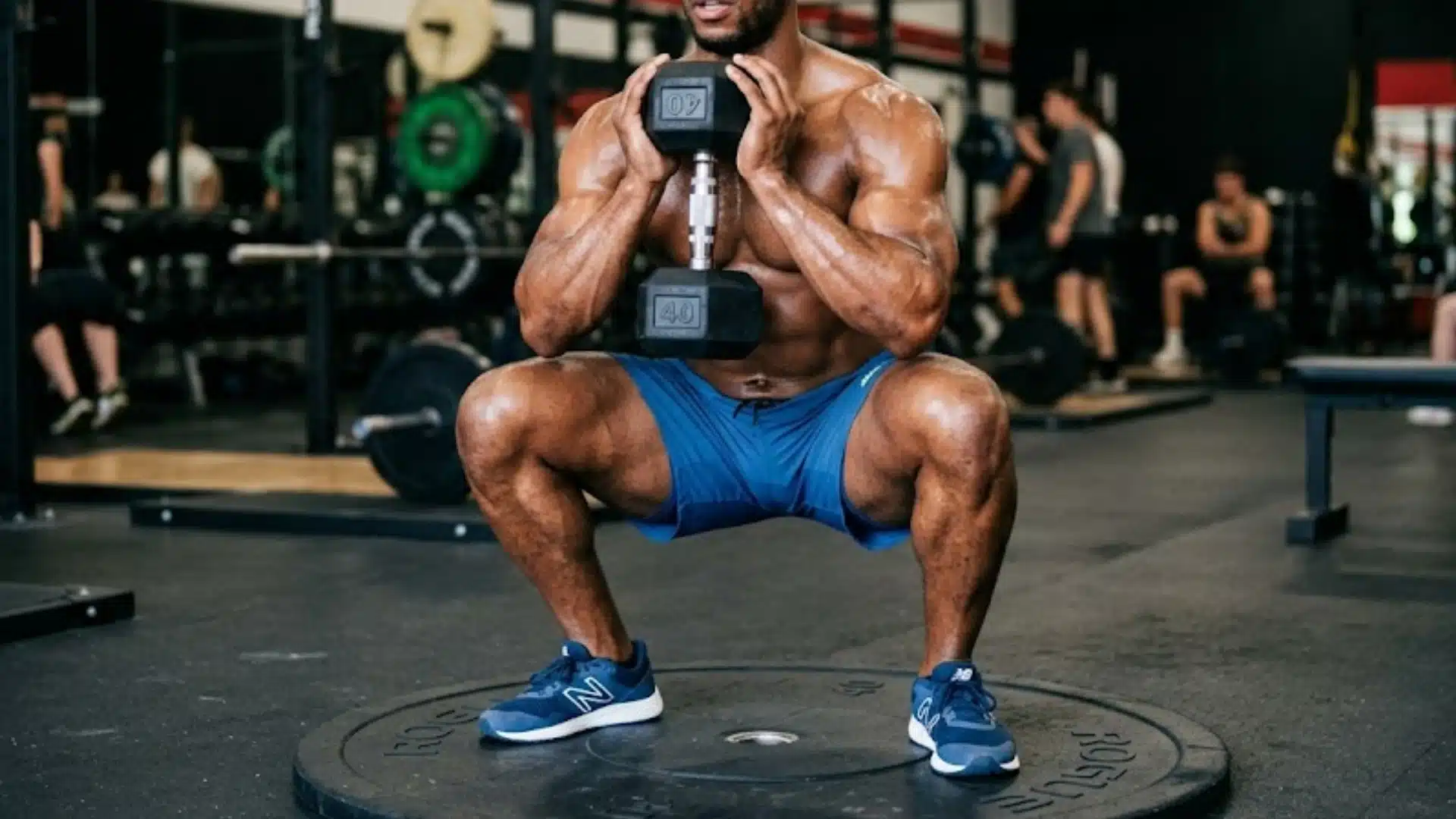 Man performing a goblet squat in gym, holding dumbbell at chest, focusing on lower body strength and balance